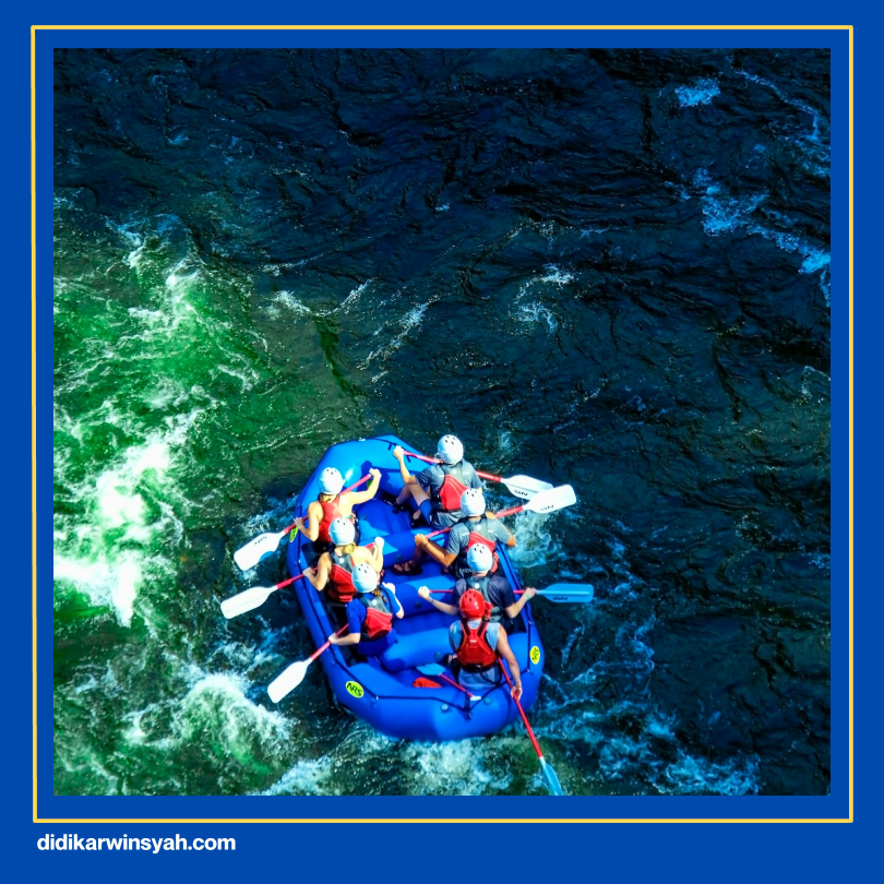 Peserta rafting mengenakan perlengkapan keamanan lengkap - helm, pelampung, dan sepatu khusus, dengan instruktur yang sedang menjelaskan prosedur keselamatan